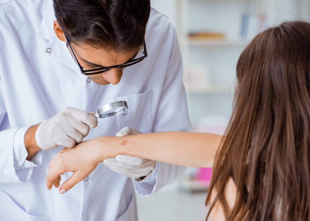Dermatologist examining patient's arm with magnifier at Fine Skin Dermatology clinic in New Lenox